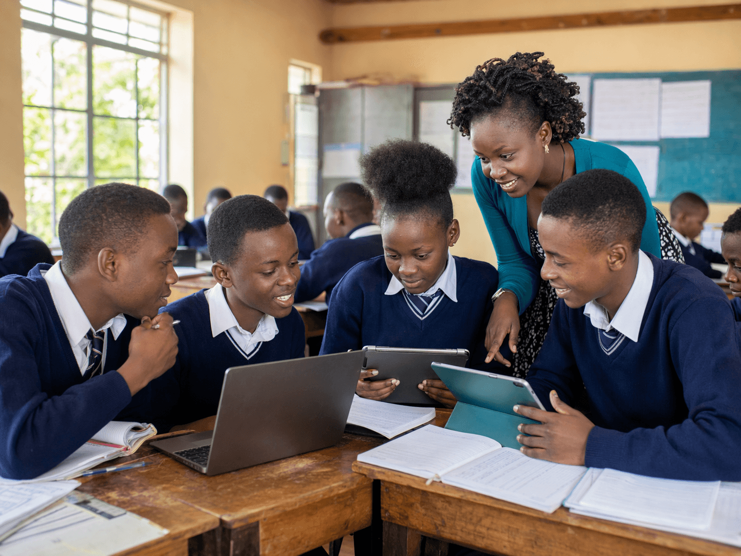 Kenyan teacher guiding students with tablets and notebooks